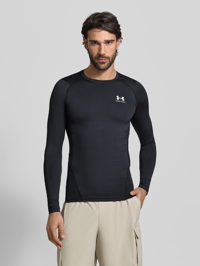 Männermodel trägt Slim Fit Longsleeve mit Logo-Print von Under Armour, schwarz, elastischer Mix, Rundhalsausschnitt, Ganzkörperansicht von vorne.