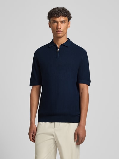 Męski model nosi Regular Fit Poloshirt aus reiner Bio-Baumwolle Modell 'CRAN' von SELECTED HOMME, granatowy, strukturalny dzianinowy materiał, kołnierzyk polo, krótki zamek, krótki rękaw, żebrowane wykończenia, widok całościowy z przodu.
