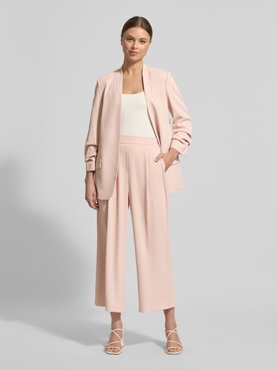 Frauenmodel trägt Stoffhose mit elastischem Bund von Jake*s Collection, Material-Mix mit Stretch-Anteil, weites Bein, gelegte Falten, Ganzkörperansicht von vorne.