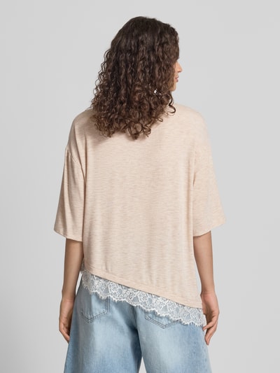 Vrouwenmodel draagt model 'GLAMOUR' t-shirt van ONLY in lichtbeige met kanten rand, dames t-shirt van ONLY, volledig silhouet achteraan.