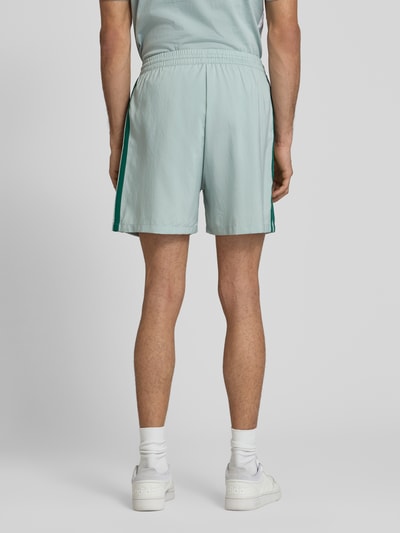 Męski model nosi Regular Fit Sport-Shorts z kontrastowymi paskami model 'CHELSEA' od adidas Sportswear, gładka faktura, logo, krój regular fit, elastyczny pas, kieszenie boczne, widok całej sylwetki z tyłu.