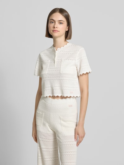Frauenmodel trägt Damen T-Shirt in Strick-Optik Modell 'Serin' von OH APRIL, Baumwoll-Viskose-Mix, Gerader-Schnitt, Muschelsaum, Label-Patch, Brusttaschen, Farbe Creme, Ganzkörperansicht von vorne.