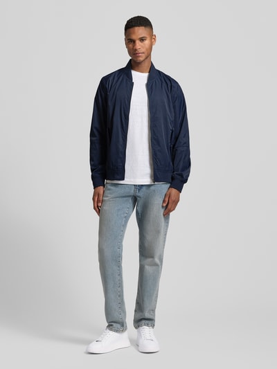 Männermodel trägt Regular Fit Bomberjacke mit Stehkragen von s.Oliver RED LABEL in Dunkelblau, unifarben, mit Reißverschluss, gerippten Abschlüssen und seitlichen Pattentaschen, Ganzkörperansicht von vorne