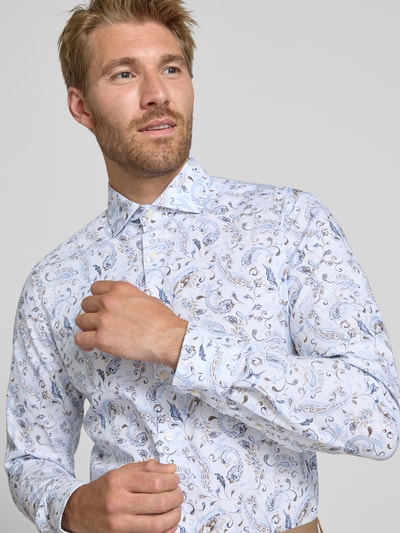 Männermodel trägt Body Fit Businesshemd aus Baumwoll-Mix von OLYMP mit blauem Paisleymuster auf Weiß, Nahaufnahme Oberkörper, Herren Businesshemd von OLYMP Level 5.