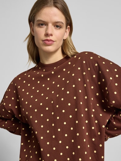 Kobiece modelka nosi Sweatshirt mit überschnittenen Schultern od OH APRIL, luźny krój, okrągły dekolt, elastyczne zakończenia rękawów, długość tyłu w rozmiarze S: 69 cm, brązowa bluza w jasne kropki, zbliżenie na górną część ciała