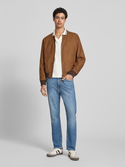 Męski model nosi Bomberjacke in Leder-Optik mit Stehkragen von Jack & Jones, krój regular fit, stójka, zamek błyskawiczny, wpuszczane kieszenie, długość tyłu w rozmiarze M: 64 cm, szerokość ramion w rozmiarze M: 45 cm, szerokość klatki piersiowej w rozmiarze M: 52 cm, długość rękawów w rozmiarze M: 67 cm, brązowe odcienie, imitacja skóry, gładka faktura, całopostaciowy widok z przodu.