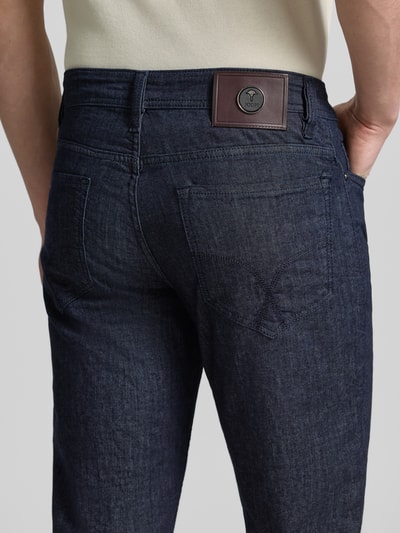 Männermodel trägt Modern Fit Jeans mit Eingrifftaschen Modell 'Fortress' von JOOP! Collection in Dunkelblau, Detailaufnahme Rückansicht, Baumwoll-Elasthan-Mix, sichtbare Gesäßtaschen und Label-Patch.