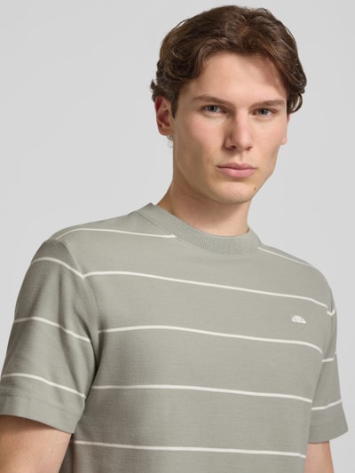 Männermodel trägt ellesse Herren T-Shirt mit Label-Stitching Modell 'VERRI', Baumwoll-Mix, Regular-Fit, Rundhalsausschnitt, Allover-Look, Nahaufnahme Oberkörper.