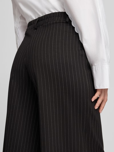 Frauenmodel trägt Regular Fit Culotte mit Bundfalten Modell 'SC-GILL 3' von Soyaconcept, schwarzes Nadelstreifenmuster, Webware, Nahaufnahme Rückansicht.