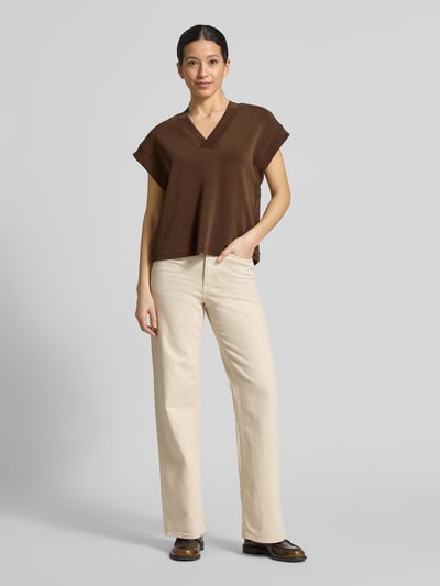 Frauenmodel trägt Relaxed Fit T-Shirt mit Lyocell-Anteil von Scotch & Soda, Damen T-Shirt aus Elastischer-Material-Mix, V-Ausschnitt, Kappärmel, Braunton auf cremefarbener Hose, Ganzkörperansicht von vorne.