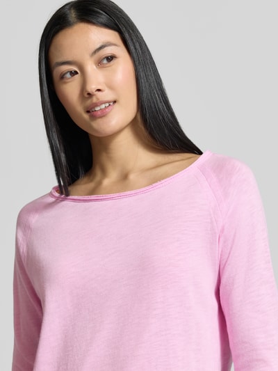 Kobiece model prezentuje sweter z dzianiny z bawełny 'Strickpullover aus reiner Baumwolle' od Rich & Royal, jasnoróżowy, luźny krój, zrolowany brzeg, raglanowe rękawy, długość tyłu w rozmiarze S: 58 cm, półzbliżenie na górną część ciała.