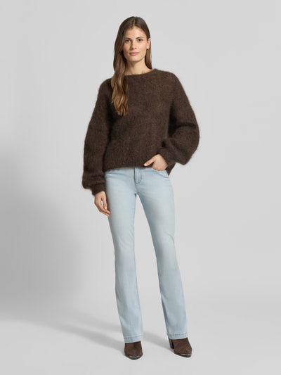Frauenmodel trägt Flared Fit Jeans im 5-Pocket-Design Modell 'Shakira' von BRAX aus elastischem Baumwoll-Mix, hellblauer Denim, Knopf- und Reißverschluss, Bundweite 36 cm, Innenbeinlänge 82 cm, Ganzkörperansicht von vorne.