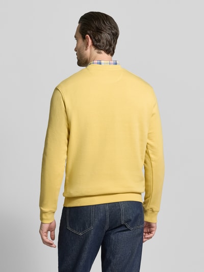 Männermodel trägt Sweatshirt mit Rundhalsausschnitt von Scotch & Soda in Gelb, Reine Baumwolle, Regular-Fit, Label-Stitching, Rückenlänge 67 cm, Ärmellänge 64 cm, Ganzkörperansicht Rückansicht.