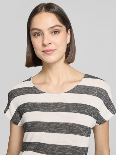 Frauenmodel trägt Regular Fit T-Shirt aus Viskose-Mix Modell 'WIDE STRIPE' von Vero Moda in Mehrfarbig mit Streifen-Design, Feinstrick, Label-Stitching-Applikation, U-Boot-Ausschnitt, Kurzarm, Rumpfabschluss abgerundet und asymmetrisch, Nahaufnahme Oberkörper.