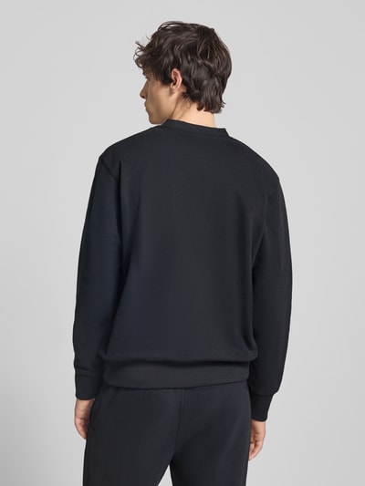 Männermodel trägt schwarzes Sweatshirt mit Rundhalsausschnitt und Label-Stitching von Ellesse, Baumwoll-Mix, Ganzkörperansicht Rückansicht.