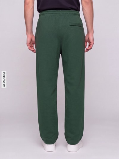 Männermodel trägt Regular Fit Sweathose aus Baumwoll-Mix von Nike in Dunkelgrün, lockerer Schnitt, Ganzkörperansicht Rückansicht, KI-modifiziertes Bild.