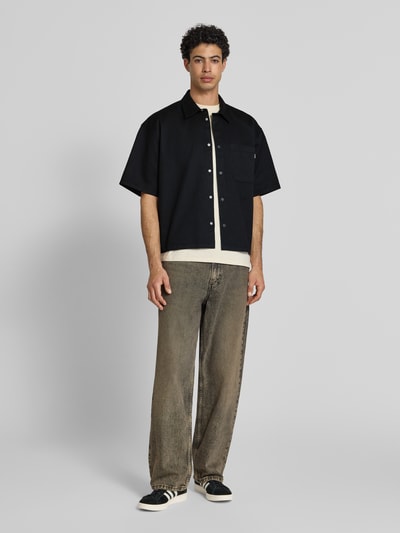 Männermodel trägt Relaxed Fit vrijetijdsoverhemd met borstzak van REVIEW in zwart met kentkraag, knoopsluiting, 1/2-mouwen, materiaalmix met katoen, heren, ruglengte maat M 67 cm, schouderbreedte 57 cm, mouwlengte 27 cm, ganzkörperansicht van voren.