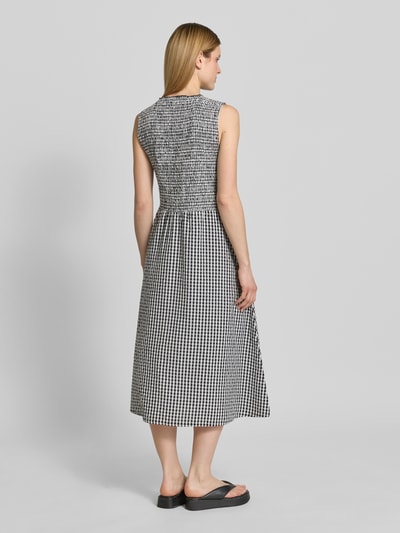 Frauenmodel trägt Midikleid mit Smok-Details und Eingrifftaschen von 7578268, Reine Baumwolle, A-Linie, karierte Muster, Ganzkörperansicht Rückansicht.
