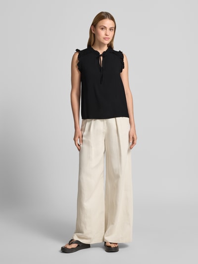 Modelka nosi Regular Fit Blusentop aus reiner Viskose Modell 'ALBA' od Vero Moda, czarny, gładka faktura, ramiączka z falbanką, widok całej sylwetki z przodu.
