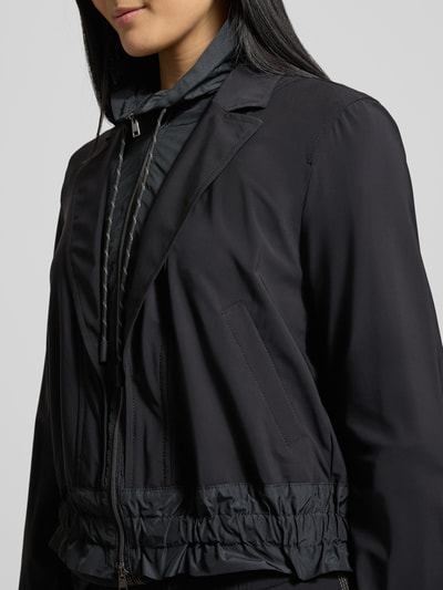 Modelka kobieca nosi Blazer mit Stehkragen od Marc Cain, czarny materiał z domieszką stretchu, regular fit, detaliczny widok górnej części ciała.