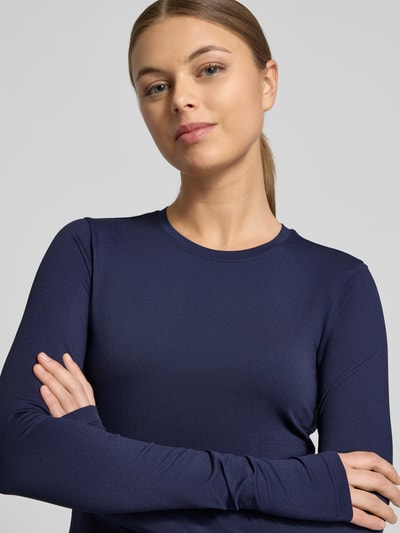 Kobiece model prezentuje Slim Fit Longsleeve mit Rundhalsausschnitt Modell 'Feather' von Fabletics, elastyczna mieszanka materiałów, krój slim fit, długość tyłu w rozmiarze S: 45 cm, granatowy, gładka faktura, zbliżenie na górną część ciała.