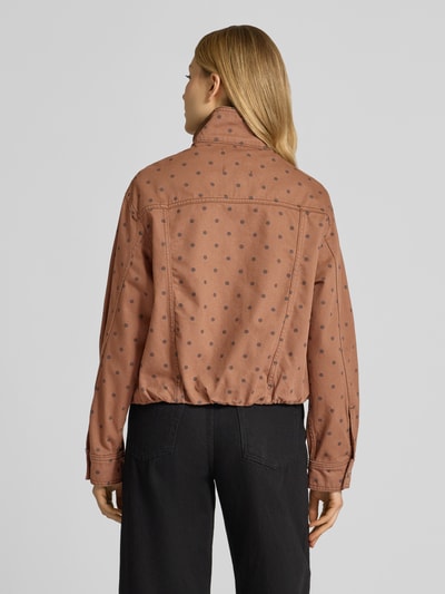Frauenmodel trägt Jacke mit verdecktem Reißverschluss Modell 'DOTS' von Mango aus reiner Baumwolle in Braun mit Punkten, Ganzkörperansicht Rückansicht