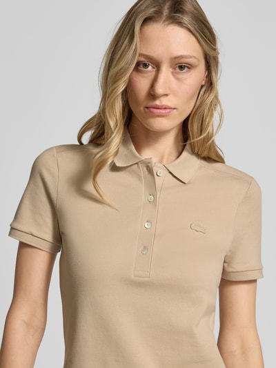 Frauenmodel trägt Slim Fit Polokleid aus Baumwoll-Mix von Lacoste in Beige, kurzarm, Piqué-Struktur, Logo-Stitching, Nahaufnahme Oberkörper.