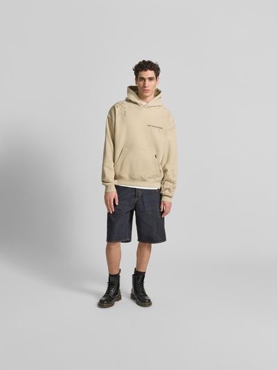 Männermodel trägt Oversized Hoodie aus Baumwoll-Mix von Don´t Waste Culture in Beige mit Florale-Stickereien, Känguru-Tasche, elastische Abschlüsse, Rückenlänge 70 cm bei Größe M, Ganzkörperansicht von vorne.