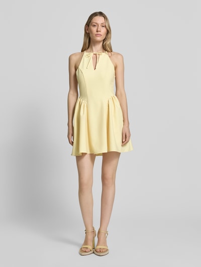 Frauenmodel trägt Cocktailkleid mit Schlüsselloch-Ausschnitt von Little Mistress in zartem Gelb, A-Linie, Rayon-Mix, Minikleid, Ganzkörperansicht von vorne. Rückenlänge 83 cm, Brustweite 40 cm, Schnürung und Rückenreißverschluss.