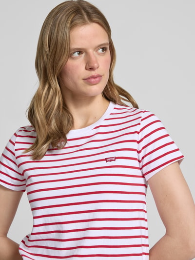 Frauenmodel trägt Regular Fit T-Shirt aus reiner Baumwolle von Levi's®, weiß-rot gestreift mit Rundhalsausschnitt, Nahaufnahme Oberkörper.
