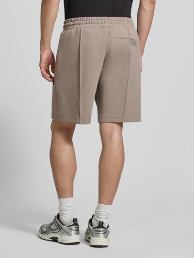 Mannelijk model draagt Regular Fit Sweatshorts uit katoenmix model 'DIMACSHORT' van HUGO, look: effen, regular fit, labelpatch, elastische boord met tunnelkoord, zij-steekzakken, materiaalverwerking: sweat, kleur is beige, mix van katoen, ganzlichaams aanzicht achterkant.