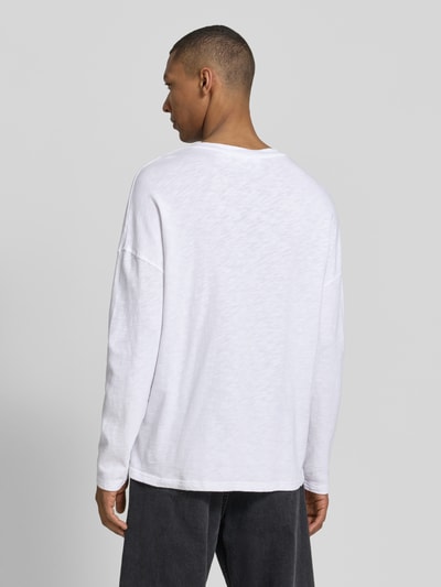 Männermodel trägt Longsleeve mit überschnittenen Schultern Modell 'SONOMA' von American Vintage in Weiß, reine Baumwolle, Regular Fit, Rückenlänge 66 cm, Ganzkörperansicht Rückansicht.