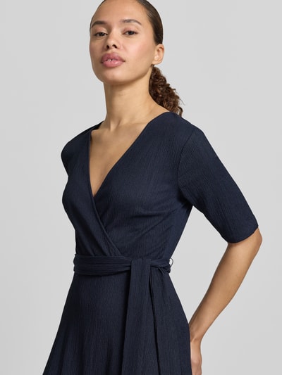 Frauenmodel trägt Wickelkleid mit V-Ausschnitt und Bindegürtel von Zero aus dunkelblauem Material-Mix mit Stretch-Anteil, Nahaufnahme Oberkörper.