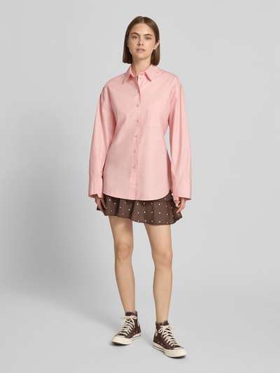 Frauenmodel trägt Oversized Hemdbluse mit Brusttasche Modell 'Demi' von Topshop in Rosa, reine Baumwolle, Ganzkörperansicht von vorne.