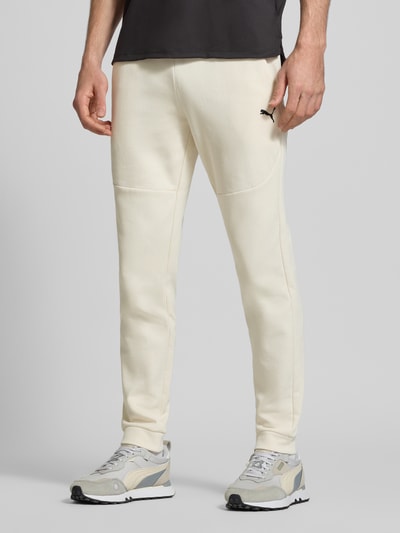 Männermodel trägt Regular Fit Sweathose mit Logo-Print Modell 'Pumatech' von PUMA PERFORMANCE aus Baumwoll-Mix, Eingrifftaschen, elastischer Bund, helle Farbe, Ganzkörperansicht von vorne.