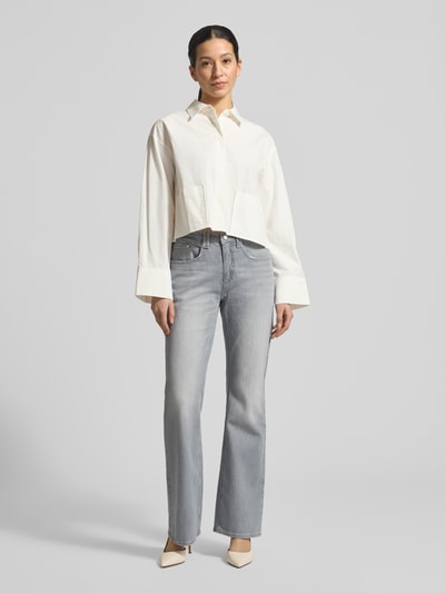 Modelka nosi Flared Jeans mit Eingrifftaschen Modell 'Mary' von BRAX, szare, rozkloszowany krój, wpuszczane kieszenie, zapięcie na guzik i zamek błyskawiczny, szerokość w rozmiarze 36: 41 cm, damskie jeansy, całopostaciowy widok z przodu.