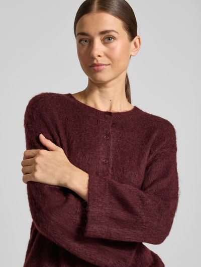 Männermodel trägt Strickjacke aus Woll-Mohair-Mix Modell 'Disille' von OPUS, kolor jednolity, faktura dzianiny, dekolt okrągły, rękaw 3/4, zakończenia prążkowane, zbliżenie na górną część ciała.