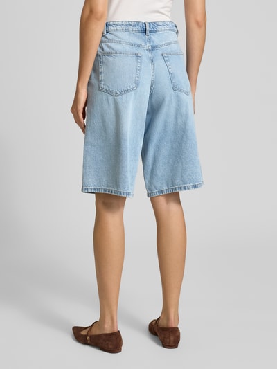 Frauenmodel trägt Regular Fit Jeansshorts aus reiner Baumwolle Modell 'SILO' von Vero Moda in hellem Denim mit Gesäßtaschen, Ganzkörperansicht Rückansicht.