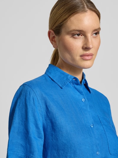 Kobiece model prezentuje Loose Fit Leinenbluse mit Brusttasche od Tommy Hilfiger z czystego lnu, kolor niebieski, z widoczną kieszenią na piersi, krój loose fit, całkowite zbliżenie górnej części ciała.
