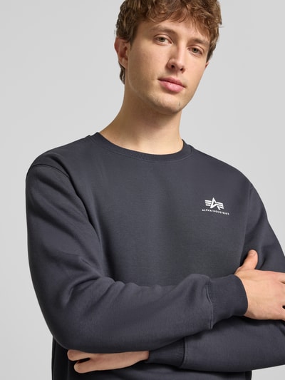 Männermodel trägt Sweatshirt mit gerippten Abschlüssen von Alpha Industries in Dunkelgrau, Baumwoll-Mix, Label-Details, Nahaufnahme Oberkörper.
