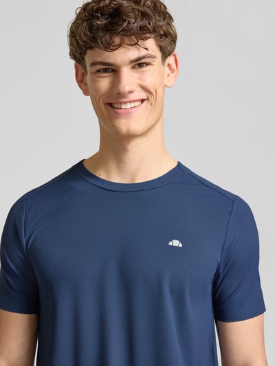 Männermodel trägt T-Shirt mit Strukturmuster Modell 'TELLER TEE' von Ellesse in Blau, Material-Mix mit Stretch-Anteil, Logo, Regular-Fit, Rundhalsausschnitt, Nahaufnahme Oberkörper.
