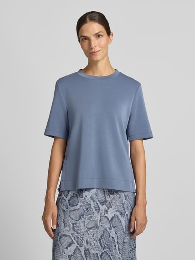 Modelka kobieca ma na sobie Sweatshirt mit Rundhalsausschnitt od Marc Cain, elastyczna mieszanka materiałów z dodatkiem wiskozy, prosty krój, okrągły dekolt, rękaw o dł. 1/2, odcień niebieskiego, gładka faktura. Widok całej sylwetki z przodu.