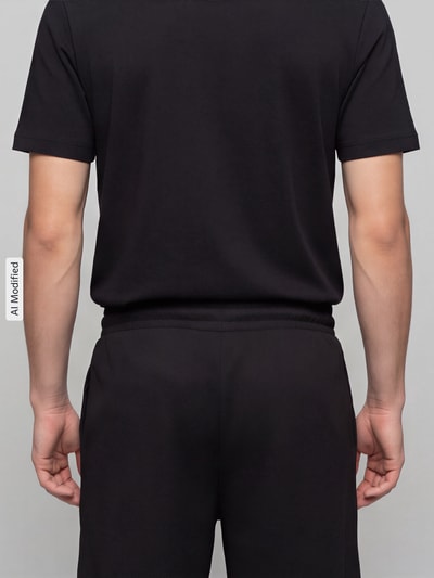 Männermodel trägt Relaxed Fit Sweatshorts aus Baumwoll-Mix 'ESS ELEVATED' von PUMA Performance in Schwarz, Ganzkörperansicht Rückansicht, KI-modifiziertes Bild.