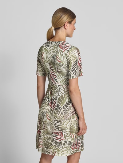 Frauenmodel trägt Knielanges Kleid im Allover-Look mit Rundhalsausschnitt von MORE & MORE, grüne, rote und cremefarbene Blätter, Material-Mix mit Stretch-Anteil, A-Linie, Rückenlänge 99 cm, Brustweite 42 cm, Ärmellänge 26 cm, Ganzkörperansicht Rückansicht.