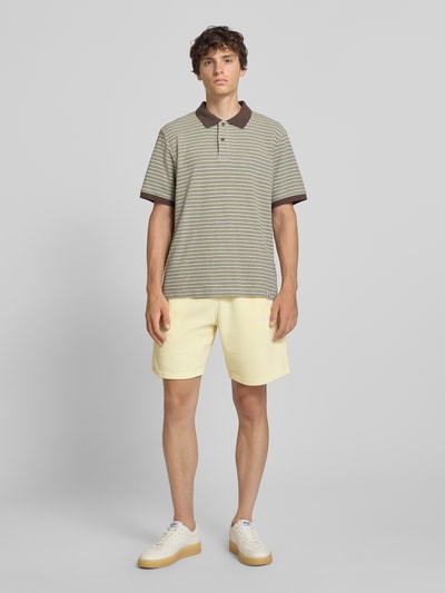 Männermodel trägt Relaxed Fit Shorts mit Strukturmuster Modell 'Lagos' von Pegador in Gelb, elastischer Bund, Ganzkörperansicht von vorne.