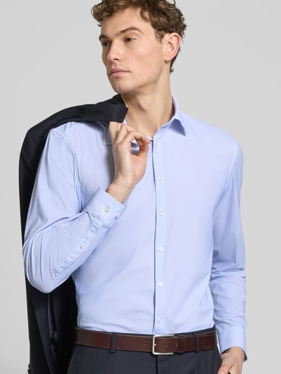 Męski model trägt Slim Fit Business-Hemd mit Kentkragen von Jake*s, elastyczna mieszanka materiałów, krój slim fit, kołnierzyk typu kent, listwa guzikowa, z długim rękawem, sportowe mankiety, długość tyłu w rozmiarze 39/40: 79 cm, szerokość ramion w rozmiarze 39/40: 45 cm, długość rękawów w rozmiarze 39/40: 67 cm, jasnoniebieski, gładka faktura, całkowity widok z przodu.