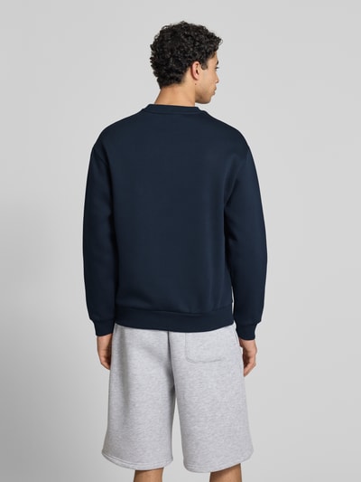 Männermodel trägt Sweatshirt mit Rundhalsausschnitt und Logo von REVIEW, mieszanka bawełny, krój regular fit, długość tyłu 70 cm, długość rękawów 62 cm, kolor granatowy, gładka tekstura, Ganzkörperansicht Rückansicht.
