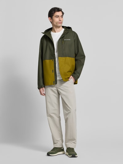 Männermodel trägt Jacke mit Kapuze Modell 'Hikebound™ II' von Columbia in Oliv und Senfgelb, Regular-Fit, Ganzkörperansicht von vorne