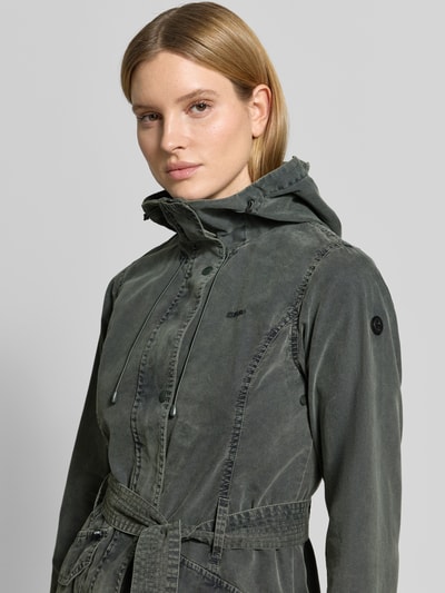 Frauenmodel trägt Jacke mit Bindegürtel Modell 'PREA' von khujo, Baumwoll-Mix, Regular-Fit, Kapuze, Label-Stitching, Nahaufnahme Oberkörper. Rückenlänge 37 cm, Schulterbreite 44 cm, Brustweite 45 cm, Ärmellänge 53 cm, Größe S. Farbton dunkles Oliv, weiche Textur, matte Optik.