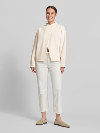 Modelka kobieca nosi Jacke Viskose-Mix mit Knopfverschluss od Rich & Royal, kolor kremowy, krój relaxed fit, długość pleców w rozmiarze S 59 cm, szerokość ramion w rozmiarze S 55 cm, szerokość klatki piersiowej w rozmiarze S 51 cm, długość rękawa w rozmiarze S 62 cm, matowa tekstura, proste kształty, pełny widok z przodu.